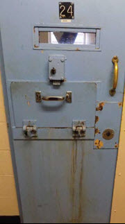 Photo de la porte d’une cellule d’isolement en train de rouiller.