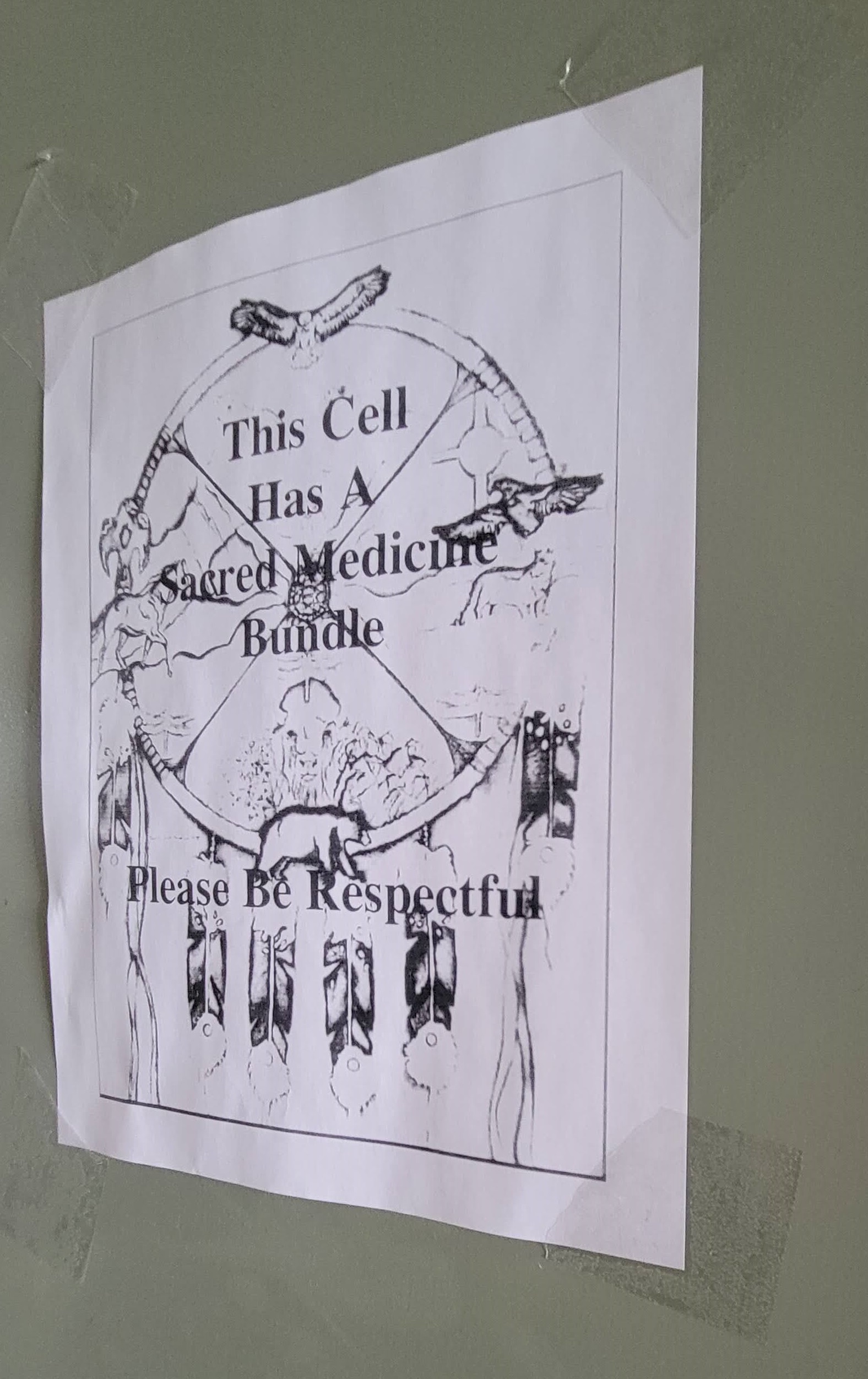 Photo d’une affiche apposée sur la porte d’une cellule des Sentiers autochtones à l’Établissement du Pacifique. L’affiche indique : « Cette cellule abrite un faisceau de médecine sacrée. Merci de la respecter. »