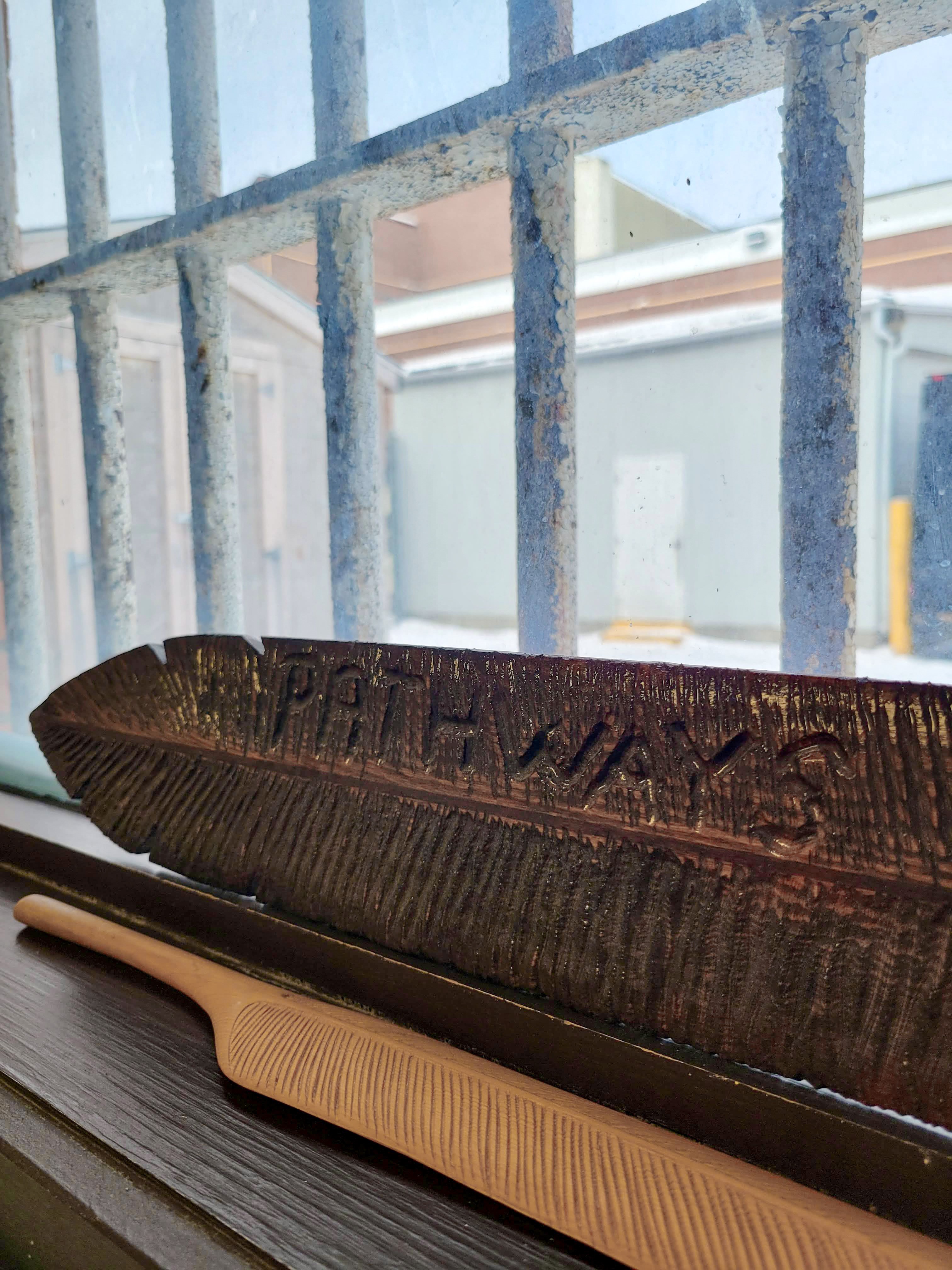 Saskatchewan Penitentiary. A feather carved out of wood with the word “Pathways” etched into it.
