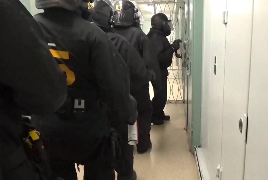 Photo d'une équipe d'intervention d'urgence alignée devant la porte d'une cellule à l'Établissement de l'Atlantique
