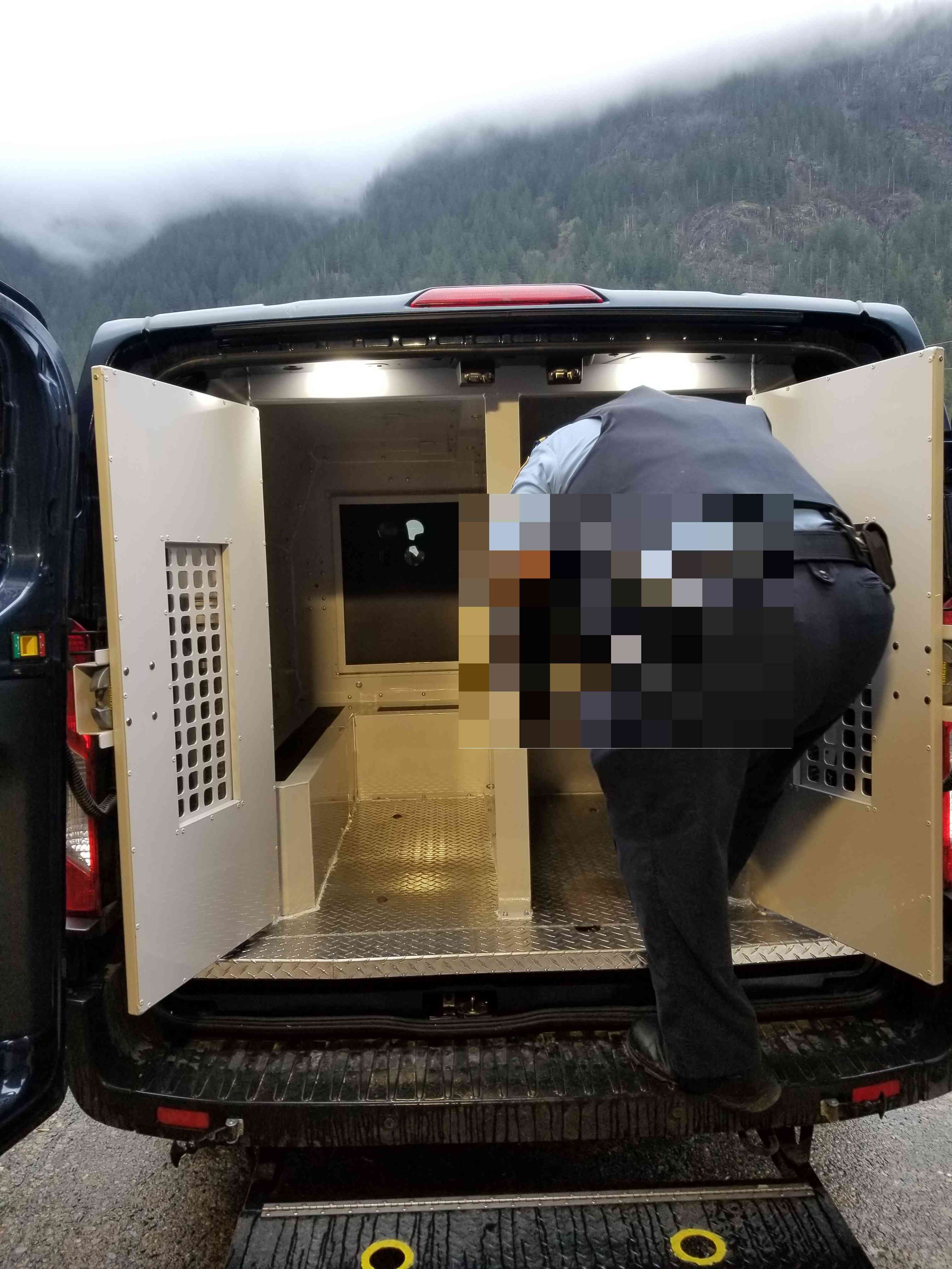 Rear view of a CSC prisoner transport vehicle with a correctional officer climbing into the prisoner compartment.