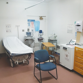 Photo of health care room with medical bed and devices.