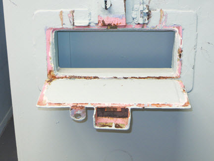 Photo de l’ouverture dans la porte d’une cellule d’isolement pour le passage des plateaux-repas.