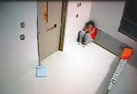 Photo d’une détenue dans le coin d’une cellule d’isolement.