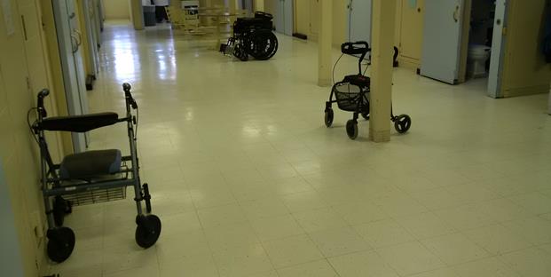 Photo d’un fauteuil roulant et de deux marchettes dans une unité réservée aux détenus âgés.